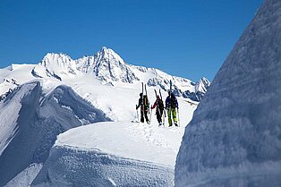 Hochalpine Skitour von drei Freunden entlang des schneebedeckten  kammes