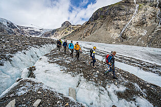 Wanderguide leittet seine Gruppe über felsigen und eiseigen Boden runter zum Tal