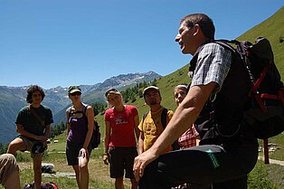 Auf dem Weg nach oben zum Berg- Wanderführer erklärt seiner Wandergruppe etwas über die grüne Natur um sie herum